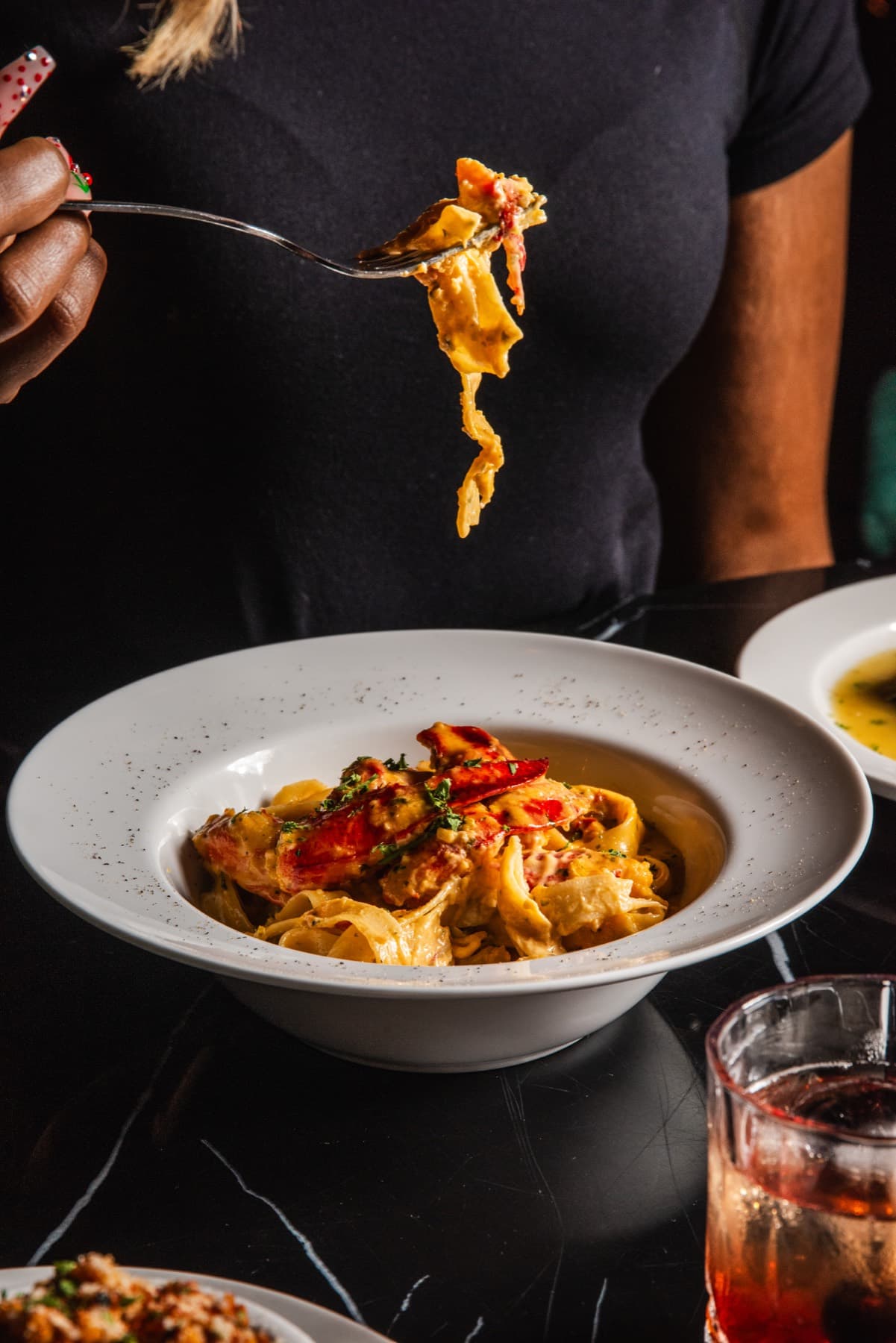 A fork lifting lobster pasta from a bowl