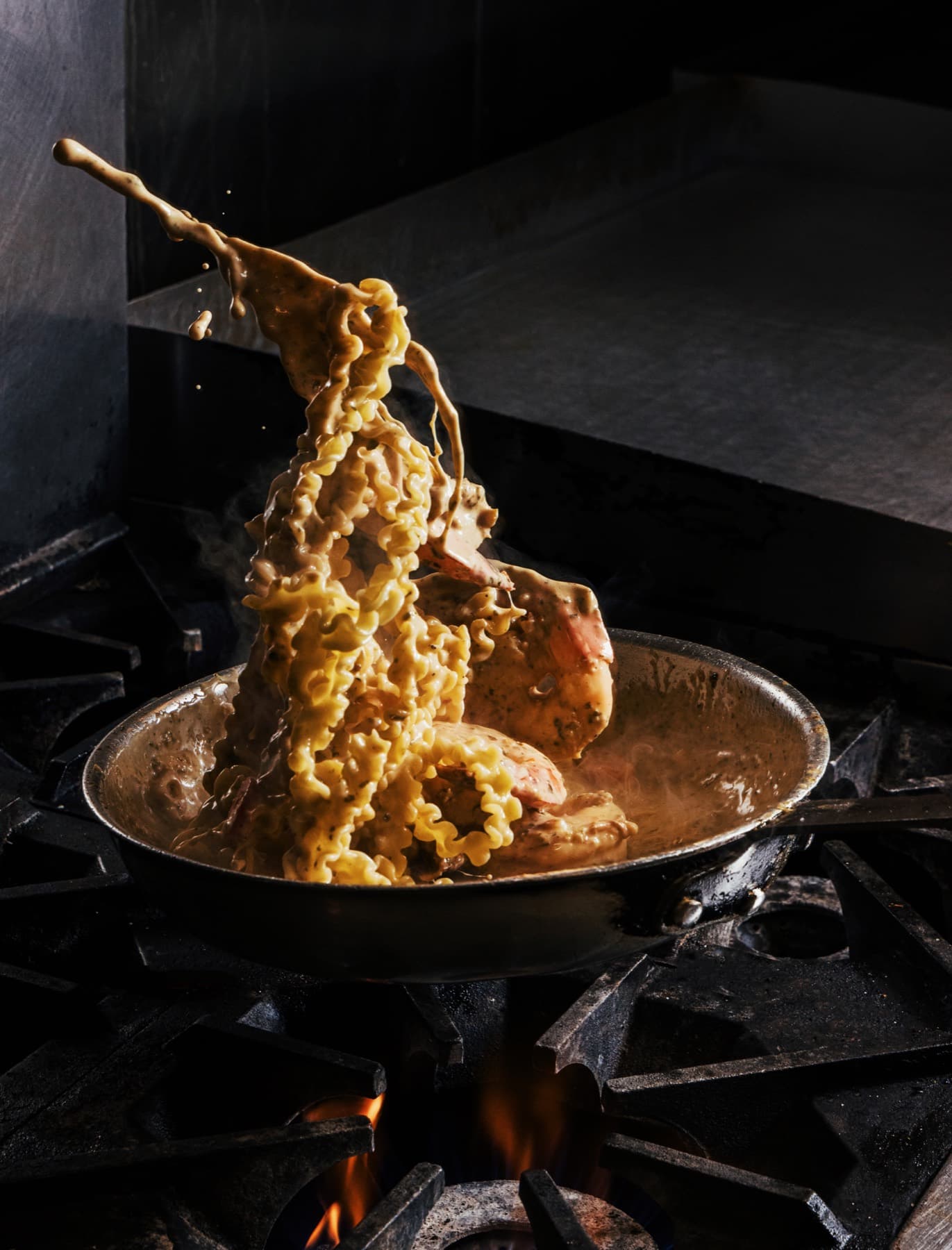 Fresh pasta tossed above a pan on the stove