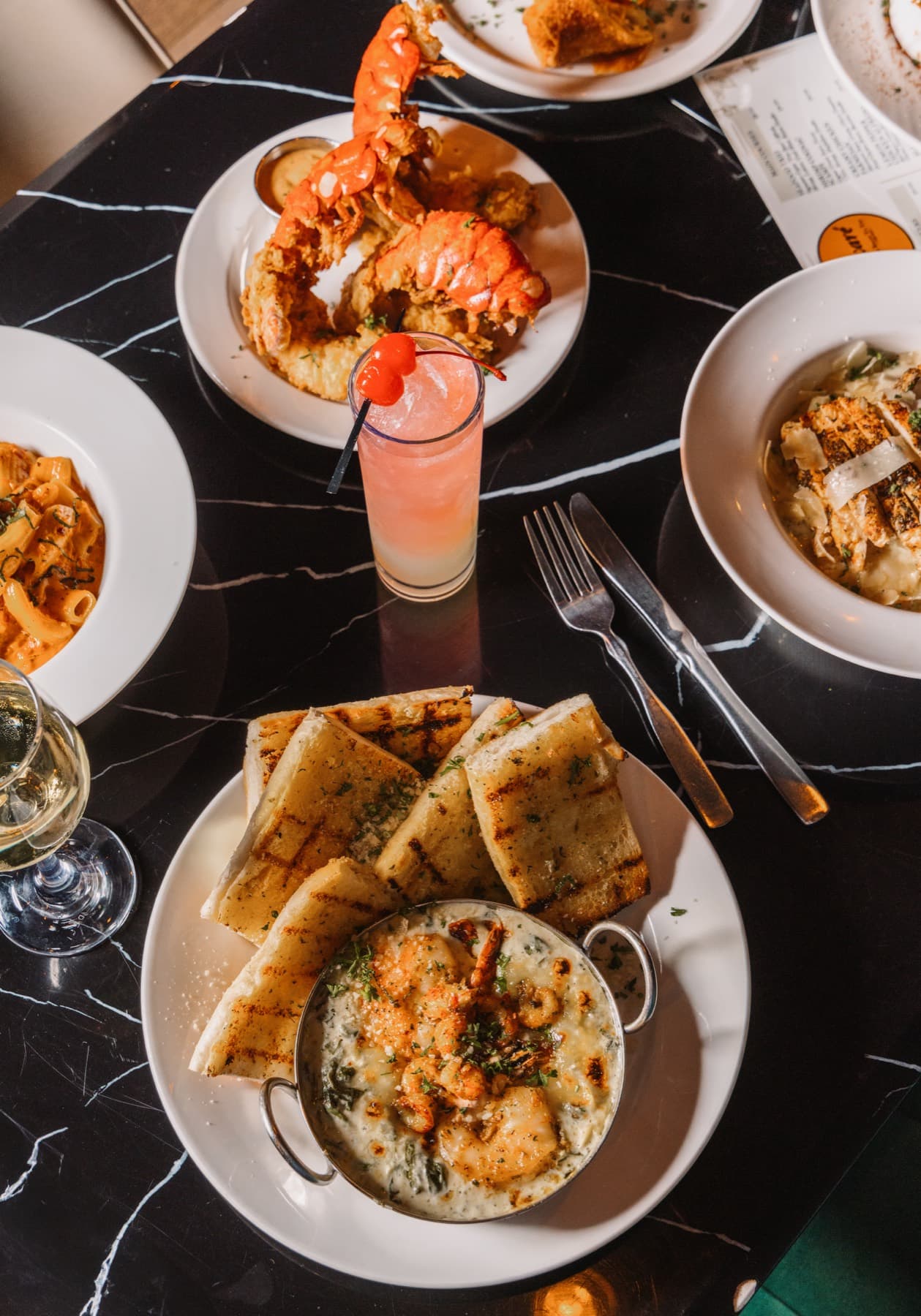 A cocktail surrounded by pasta and seafood dishes